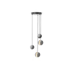 Four Clérachic concrete pendants hang from a round black canopy on white at different drops, two lit through the slot.