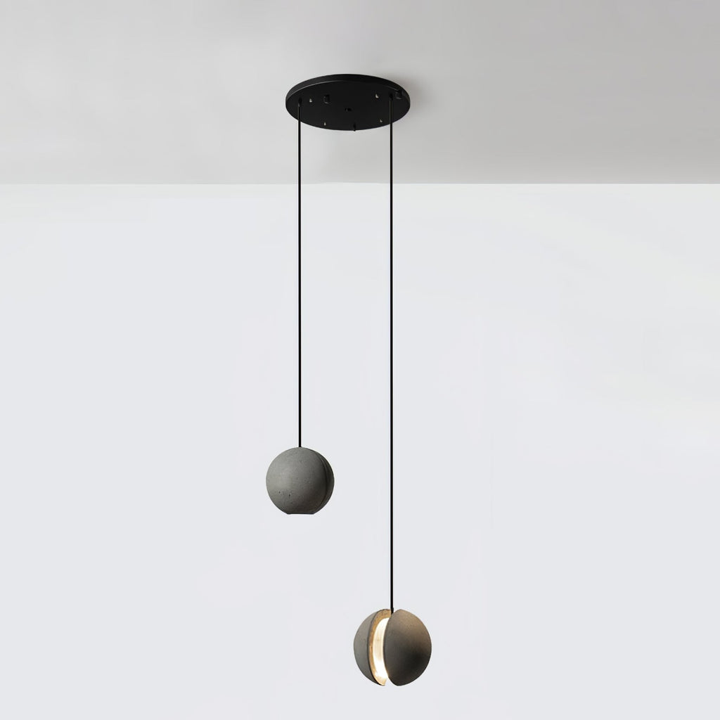 Two Clérachic concrete pendants hang from a round black canopy at different heights against a white wall.