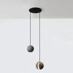 Two Clérachic concrete pendants hang from a round black canopy at different heights against a white wall.