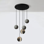 Five Clérachic concrete pendants hang from a wide round black canopy at staggered heights against a white wall.