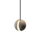 A Clérachic concrete pendant with a split shell glows warmly through the opening between its two halves.