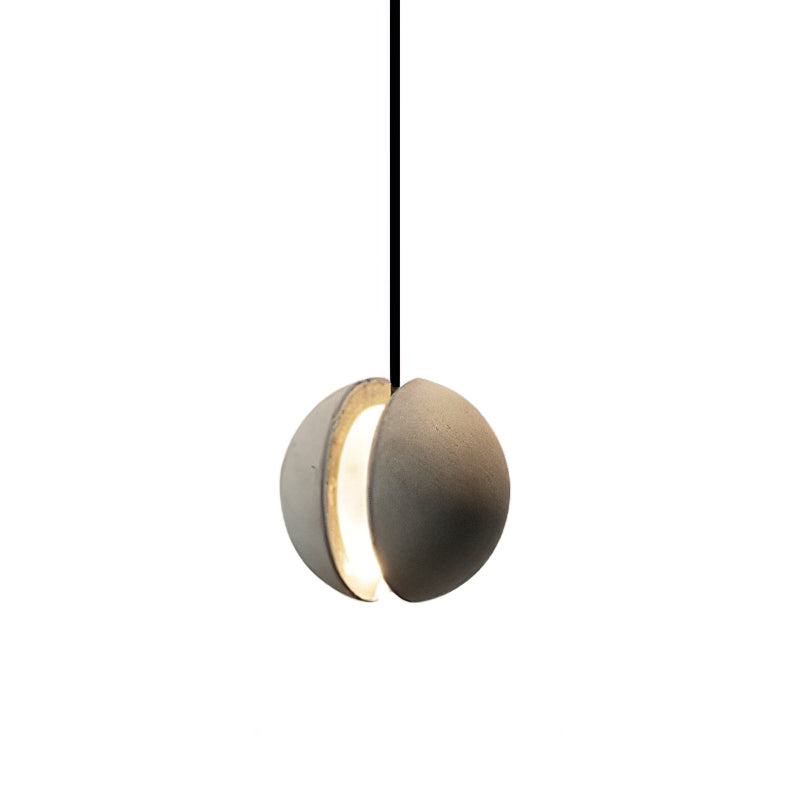 A Clérachic concrete pendant with a split shell glows warmly through the opening between its two halves.