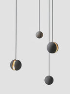 Four Clérachic concrete pendants hang at different heights against light grey, two of them with a warm lit slot.