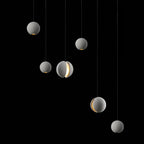 Six Clérachic concrete spheres hang against black, pale grey in tone, with two showing a bright lit crescent.