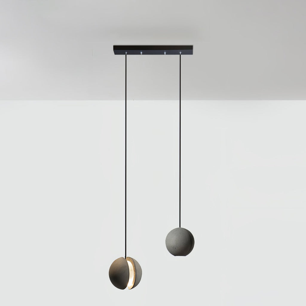 Two Clérachic concrete pendants hang from a short black bar canopy, the lower one glowing through its slot.