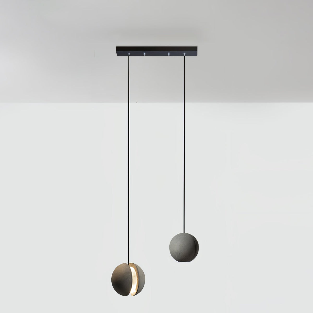 Two Clérachic concrete pendants hang from a short black bar canopy, the lower one glowing through its slot.