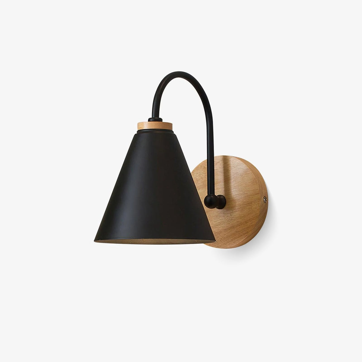 Black conical shade on a curved metal stem with a round wooden backplate, this Clérachic wall light on a plain white backdrop.