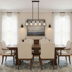 Two black Clérachic wall lights frame a landscape painting above a wooden dining table with cream chairs and a lantern-style pendant.