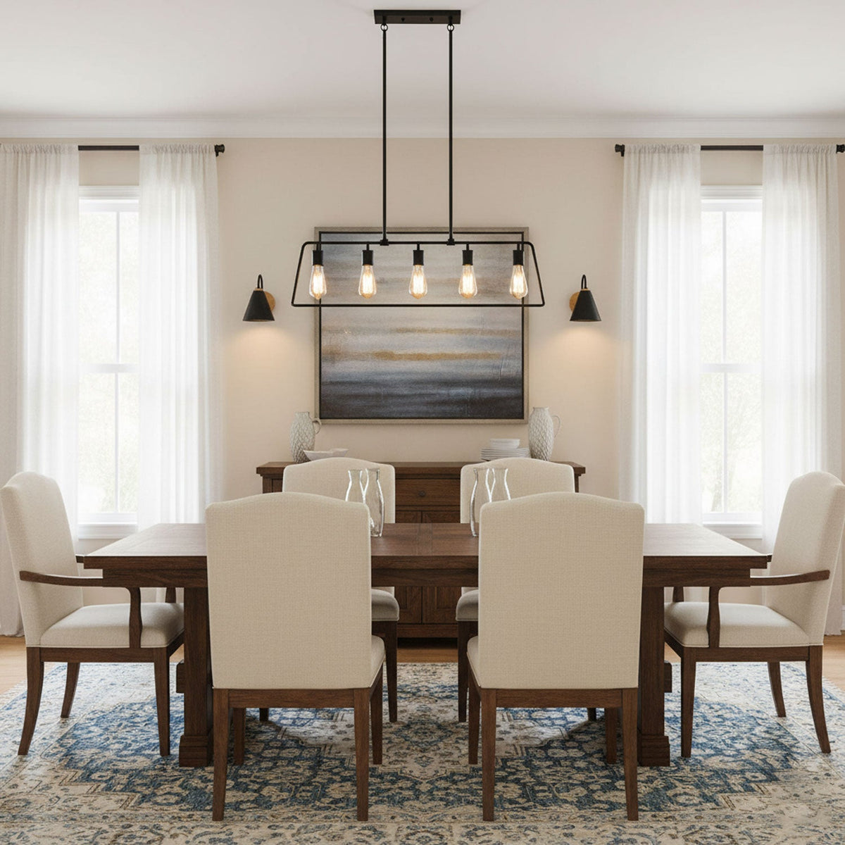 Two black Clérachic wall lights frame a landscape painting above a wooden dining table with cream chairs and a lantern-style pendant.