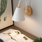 White Clérachic wall light with a wooden backplate above an open book, with a cactus print behind it.