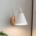 Close view of this white Clérachic wall light with a curved stem, glowing softly on a grey wall with a plant at lower left.
