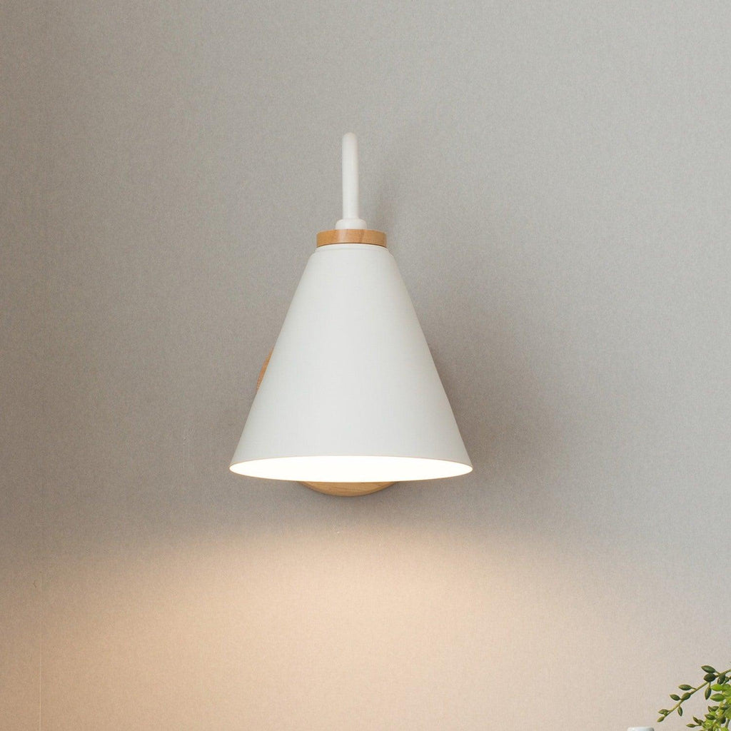 White cone shade with a short upturned stem, this Clérachic wall light seen from the front on a grey wall.