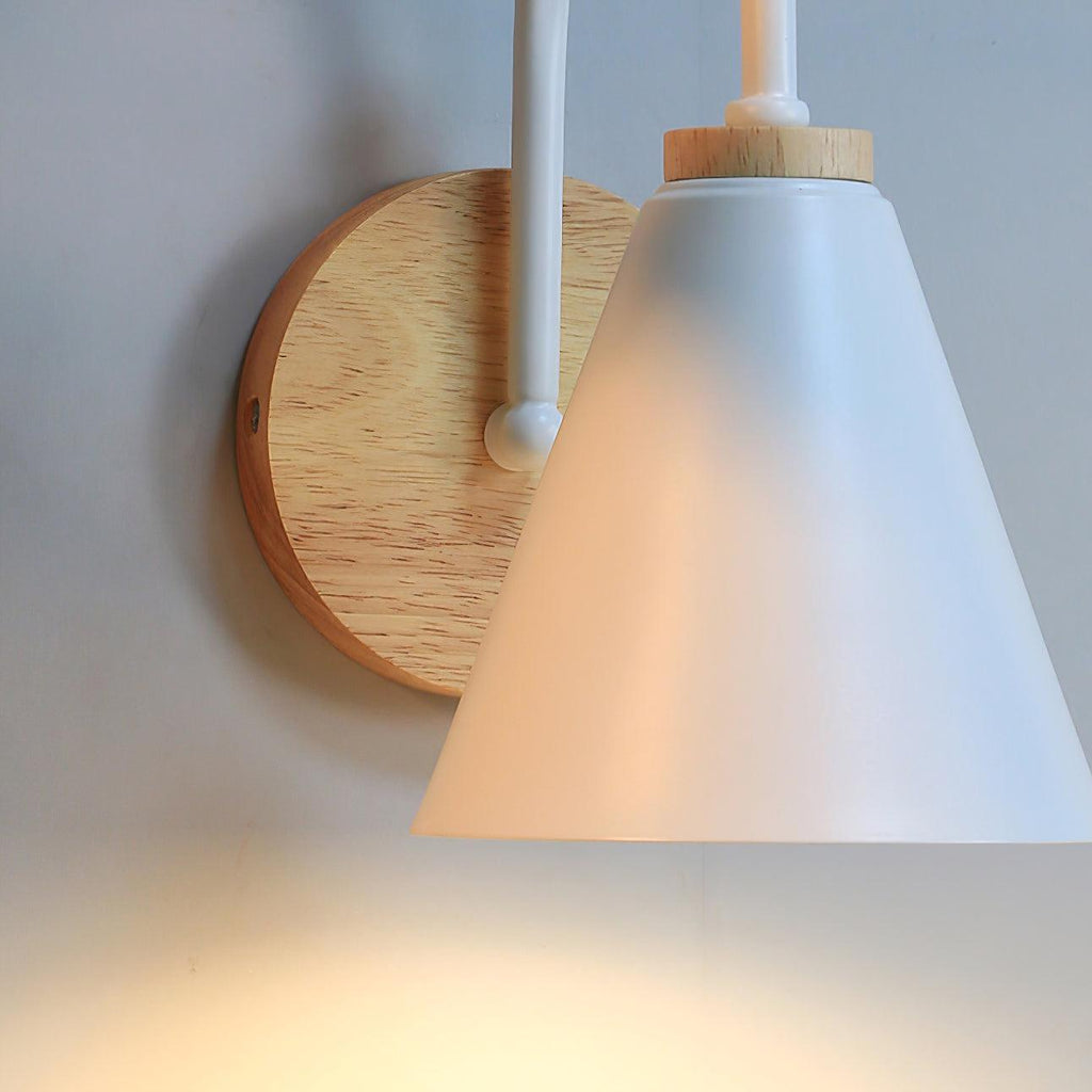 Wooden backplate with visible screws and the white cone shade of this Clérachic wall light, shown from the side with a warm glow.