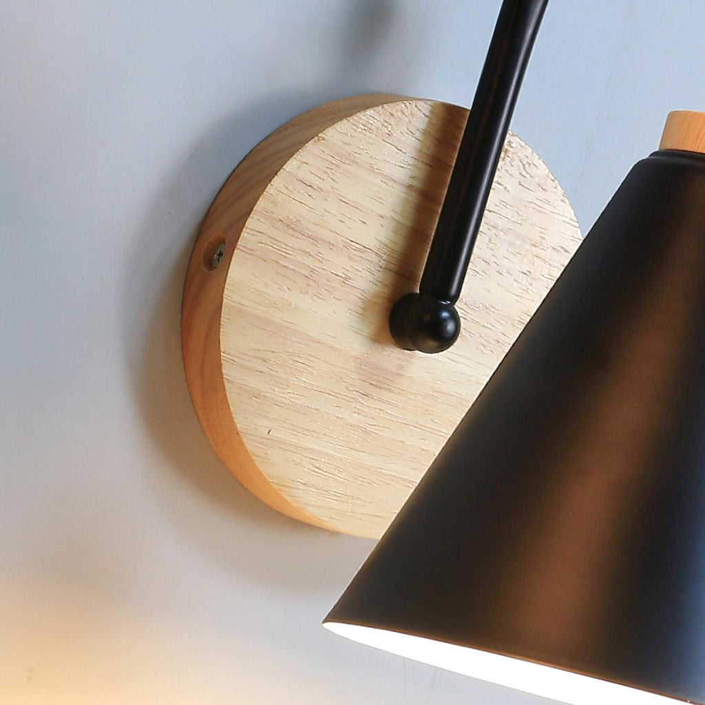 Close view of the wooden backplate and black ball joint on this Clérachic wall light, with the black shade at the right.