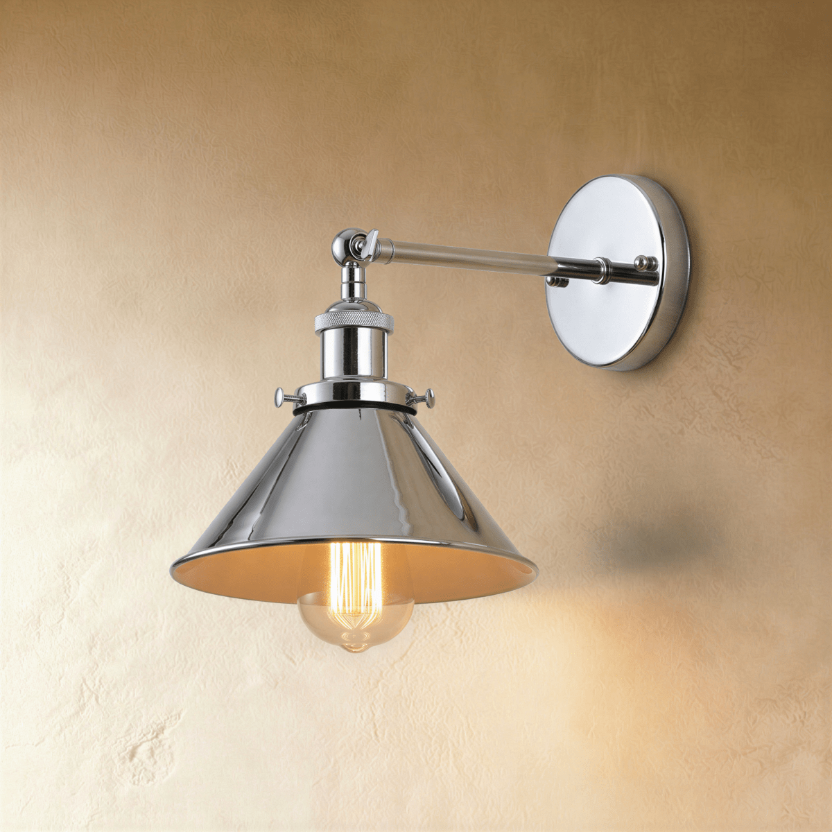 Clérachic wall lamp in polished chrome with a wide cone shade, jointed arm and round backplate, lit by a warm filament bulb.