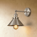 Clérachic wall lamp in brushed nickel with a wide cone shade, knurled collar and round backplate, an amber filament bulb below.