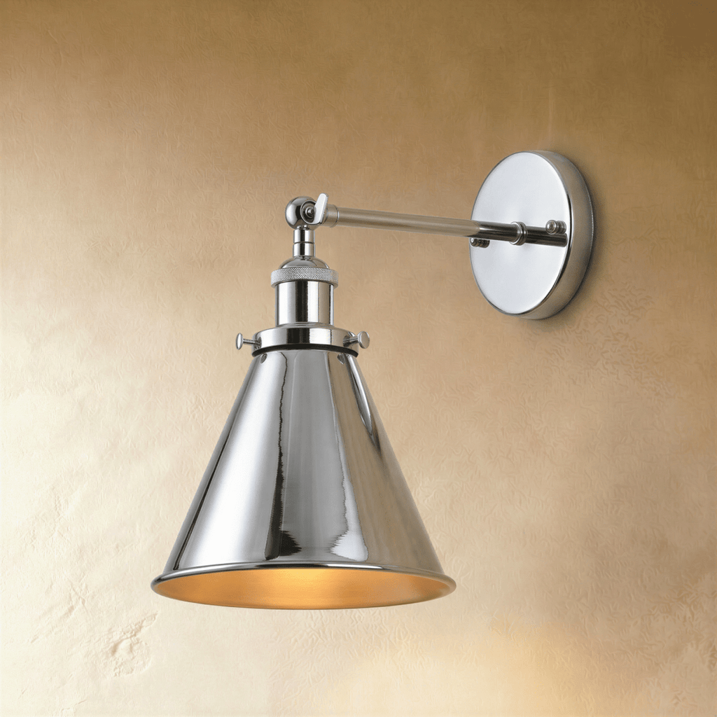Clérachic wall lamp in polished chrome with a narrow cone shade, gold-toned interior and a jointed arm on a warm plaster wall.