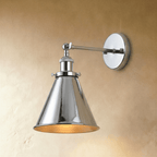 Clérachic wall lamp in polished chrome with a narrow cone shade, gold-toned interior and a jointed arm on a warm plaster wall.