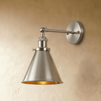 Clérachic wall lamp in brushed nickel with a narrow cone shade, a gold-toned inner surface and a round backplate.