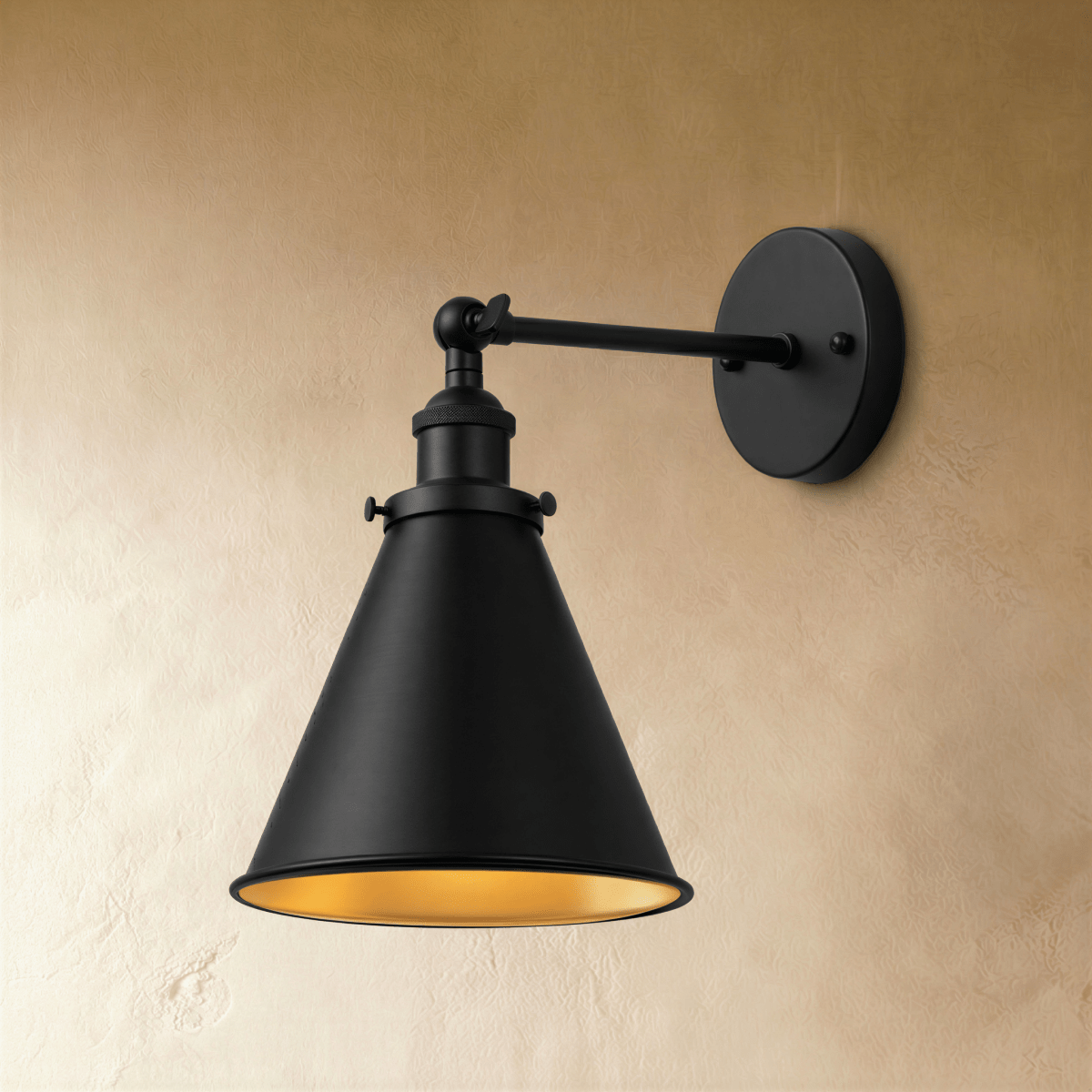 Clérachic all-black wall lamp with a narrow cone shade, gold-toned inner surface and a jointed arm on a plaster wall.