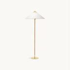 Clérachic floor lamp with a wide white fabric cone shade on a slim wrapped stem and round brass base, on a plain off-white backdrop.