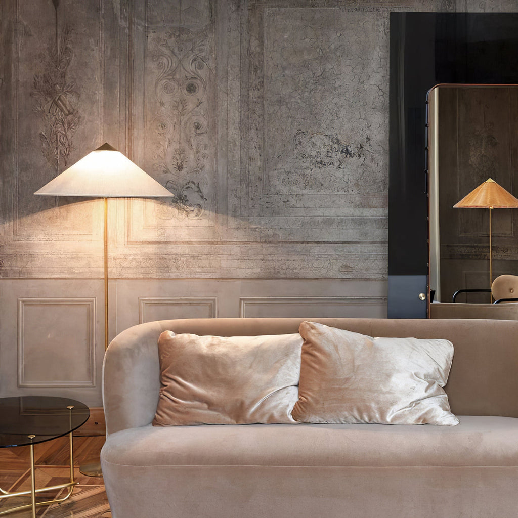 This Clérachic floor lamp glowing beside a dusty-pink velvet sofa, against a softly worn grey plaster wall.