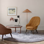 Clérachic floor lamp with a rattan cone shade behind a glass-top round table, a mustard armchair and a grey round rug.