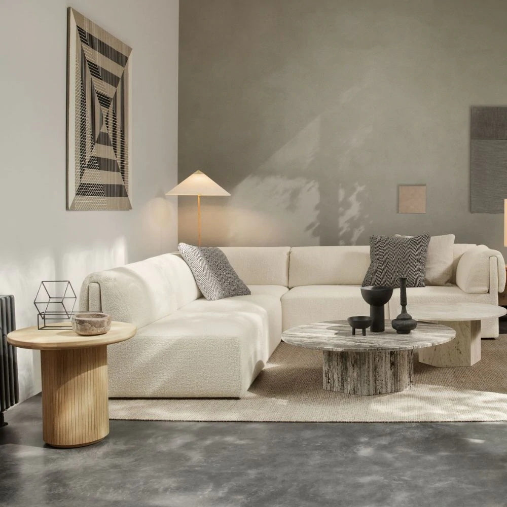 Clérachic floor lamp with a small cone shade behind a large cream corner sofa, with a stone coffee table and a round wood side table.