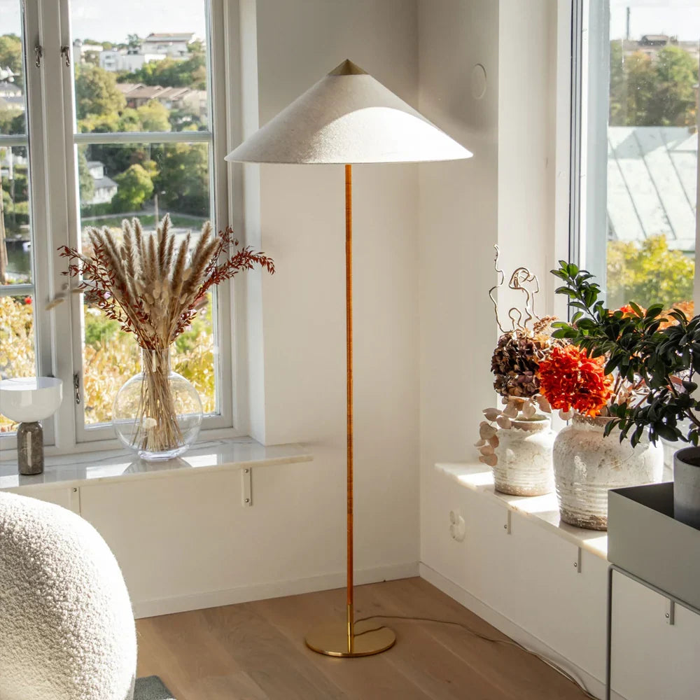 Standing floor lamp from Clérachic with a textured cream cone shade by a bright window sill with dried grasses and bright orange flowers.