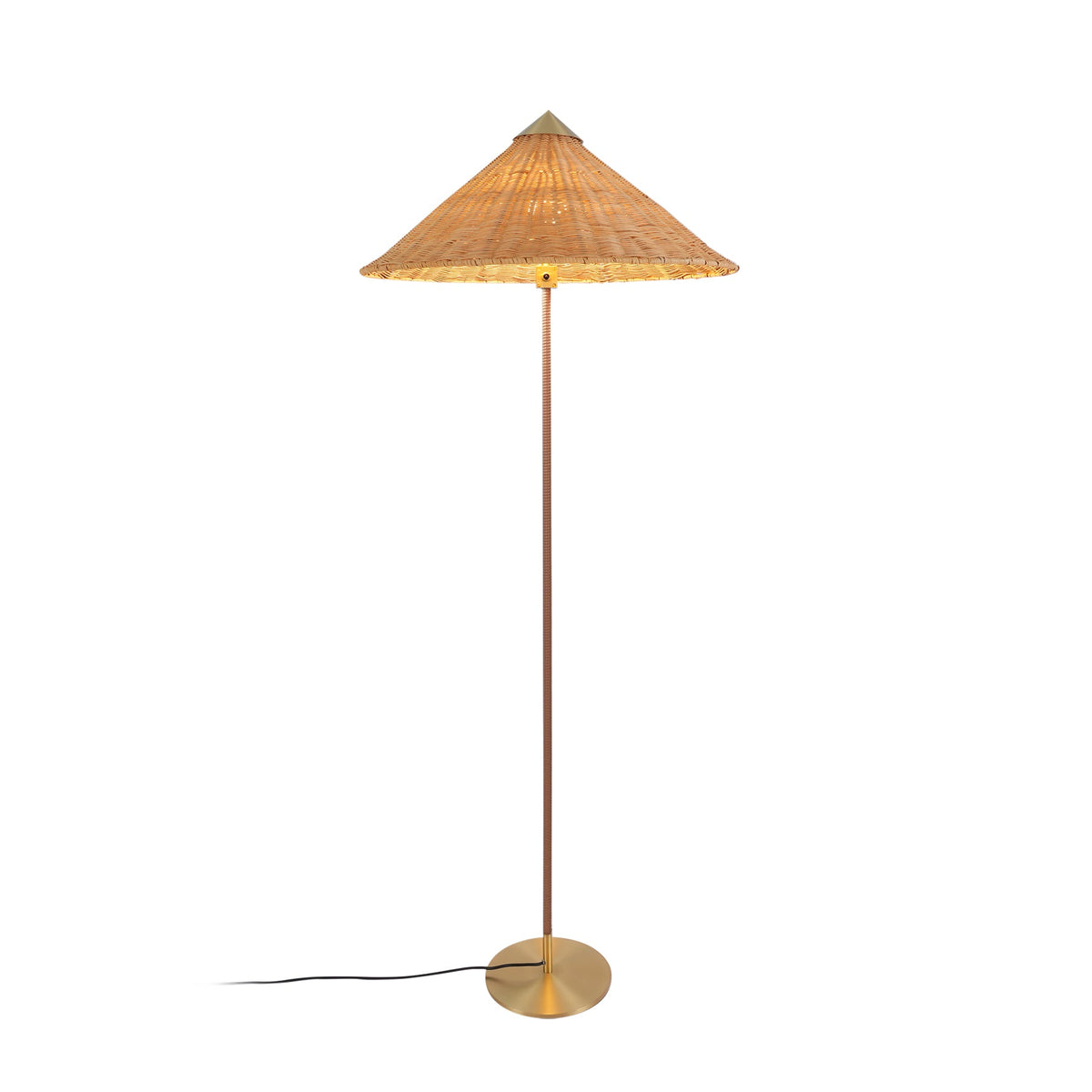 Clérachic floor lamp with a natural rattan cone shade and a brass base, its black cord trailing to the left on white.