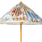 A Clérachic floor lamp's printed fabric shade with a tiger and birds, seen close, with the brass cap and rattan-wrapped stem.
