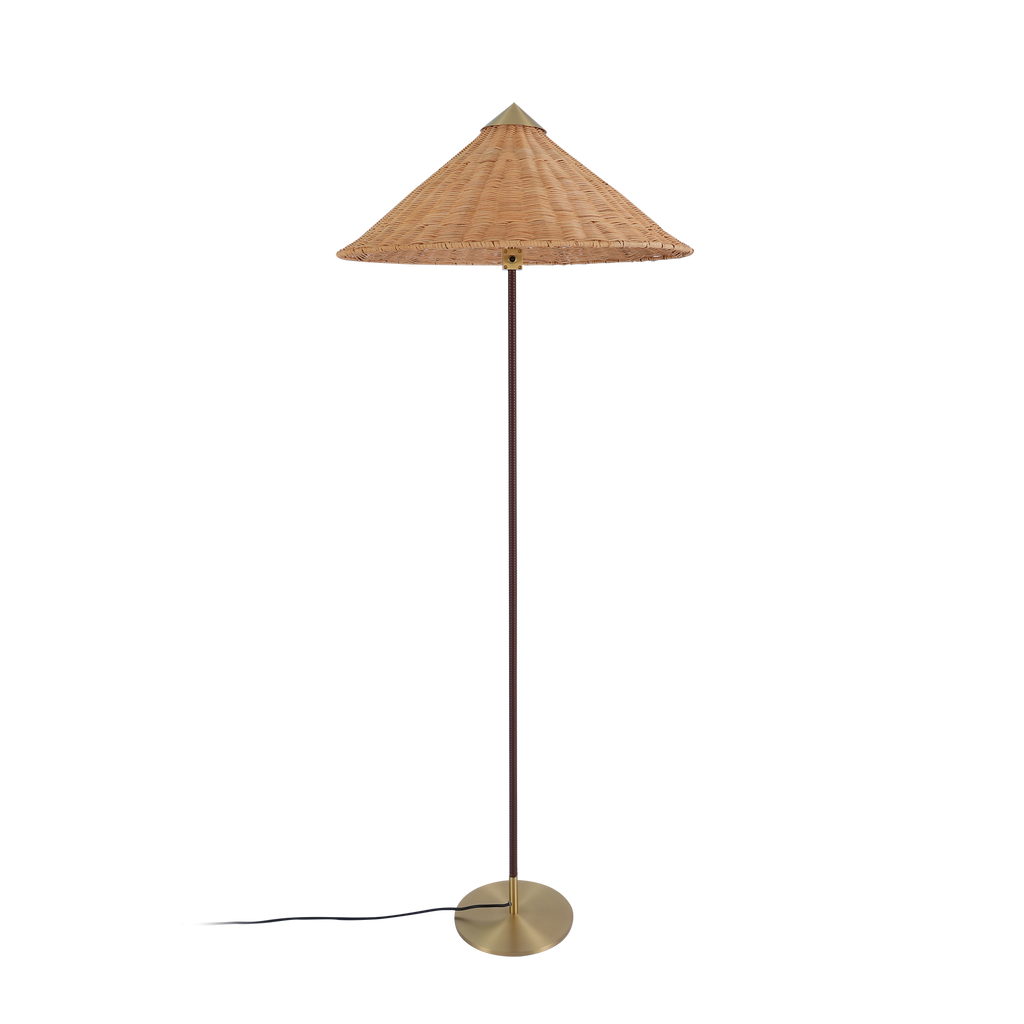 A Clérachic floor lamp with a rattan cone shade and a dark brown stem, its cord at the base, on a black backdrop.