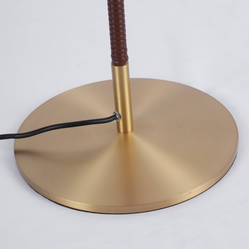 Close view of the round brushed brass base, the brown wrapped stem and the black cord on this Clérachic floor lamp.