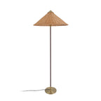 Clérachic floor lamp with a woven rattan cone shade and a thin dark stem, on a round brass base, on white.