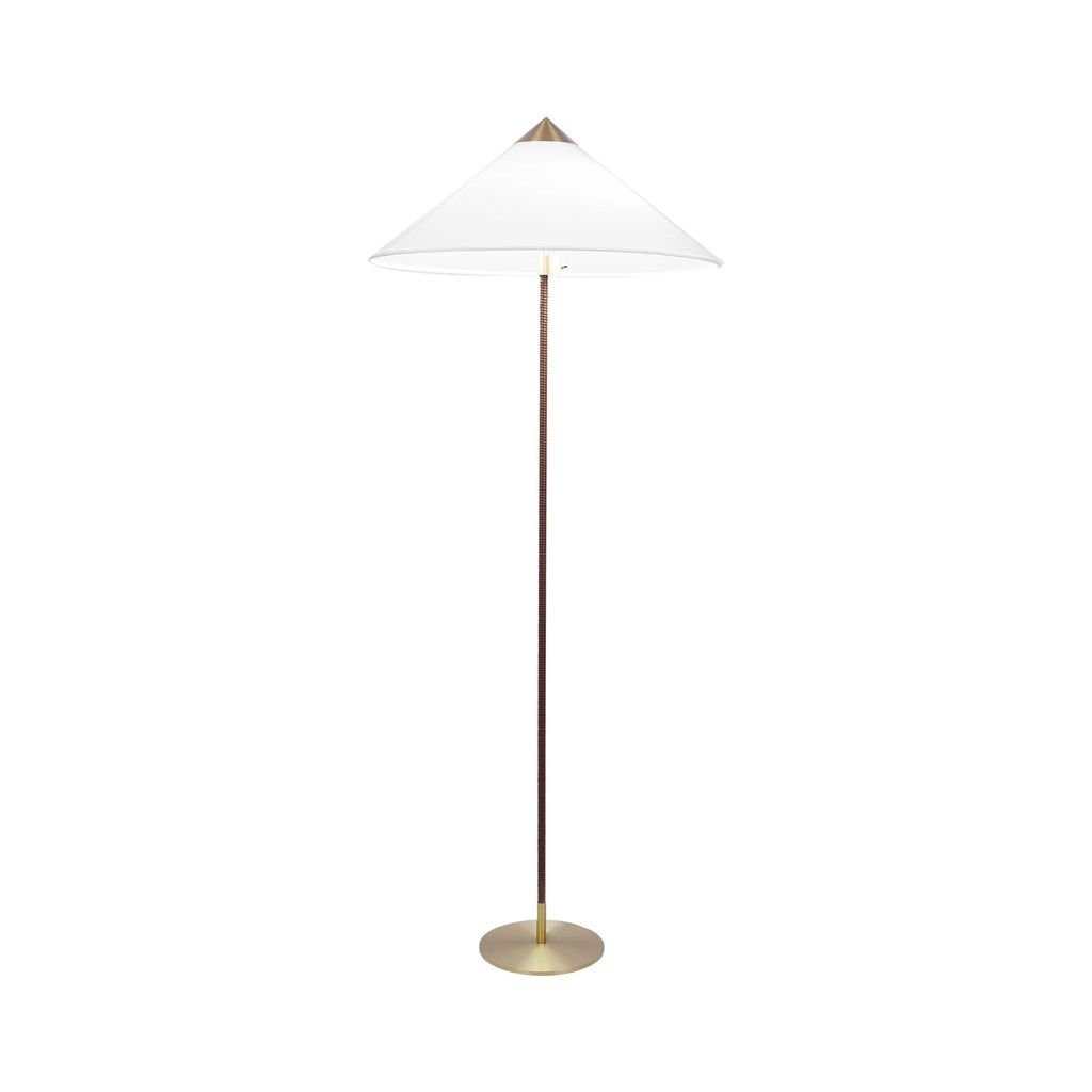 Floor lamp by Clérachic, with a white fabric cone shade, a dark stem and a brushed brass base, on white.
