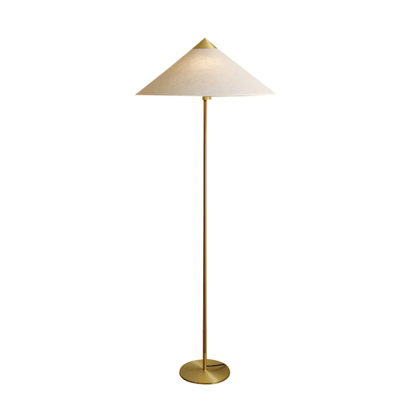 Clérachic floor lamp with a linen cone shade, a wrapped stem and a brass base with the cord at its foot, on white.