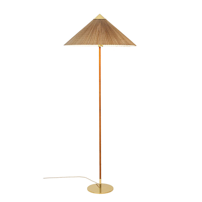 Clérachic floor lamp with a slatted bamboo cone shade and a cane-wrapped stem, its pale cord running left from a brass base.