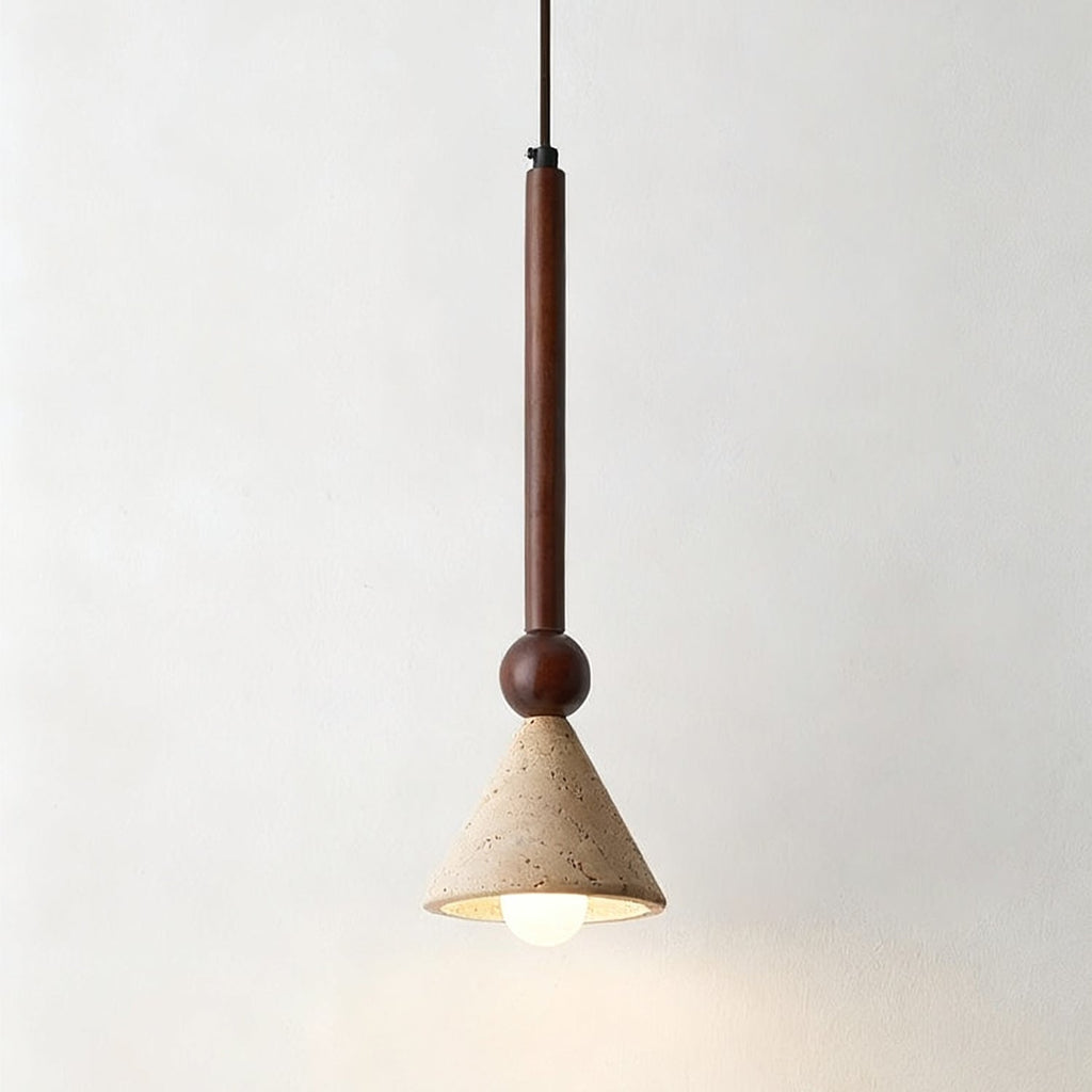 Close view of a travertine cone shade with its natural pores, hanging from a walnut stem against a pale wall, from Clérachic.