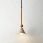 Warm bulb glowing inside a travertine cone shade on a light wooden stem and bead, against a pale wall, from Clérachic.