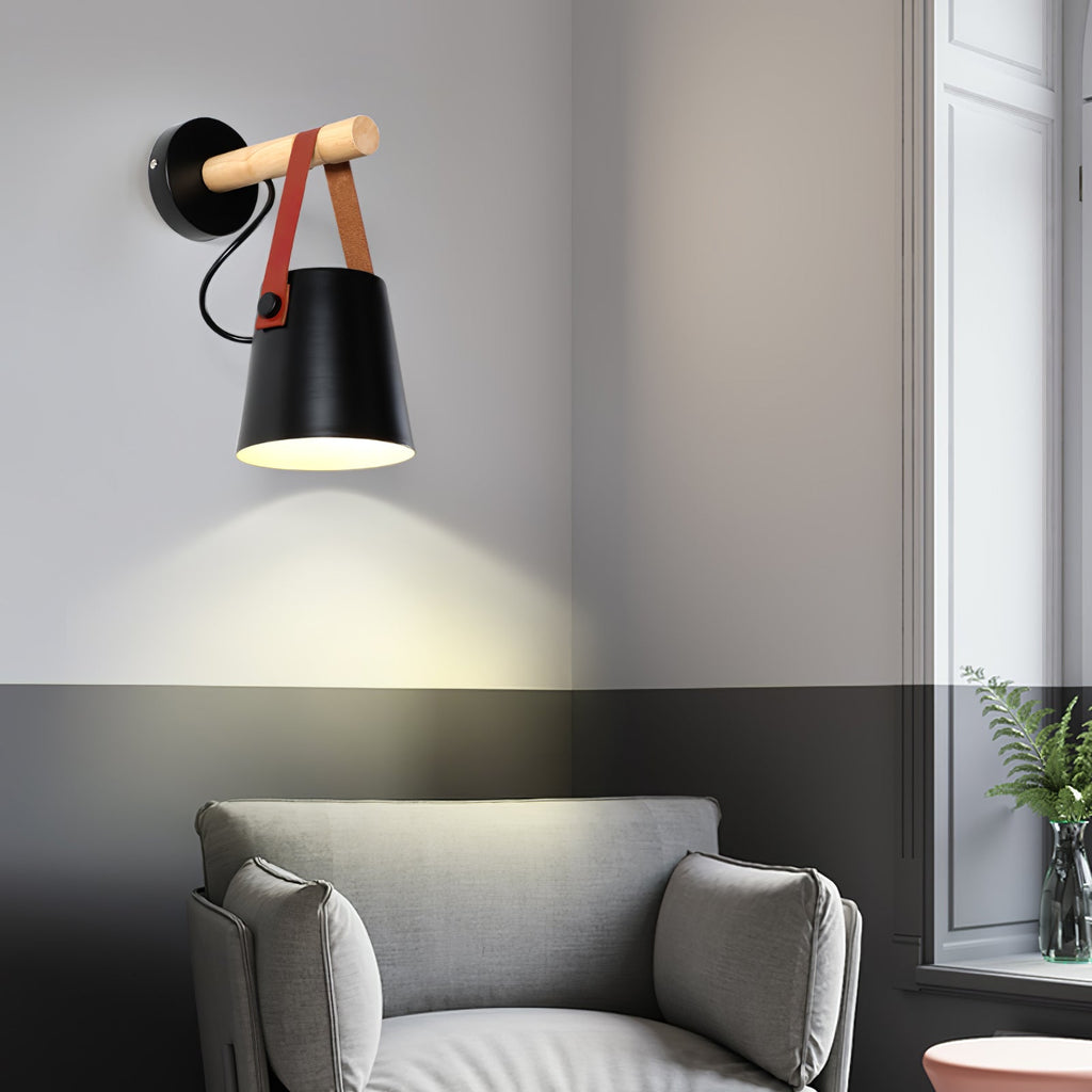 Black Clérachic wall light glowing above a grey armchair, with a two-tone wall in grey and charcoal and a window beside it.