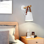 White Clérachic wall light with a wooden bar above a bed with an oak headboard and a bedside table holding a small clock.