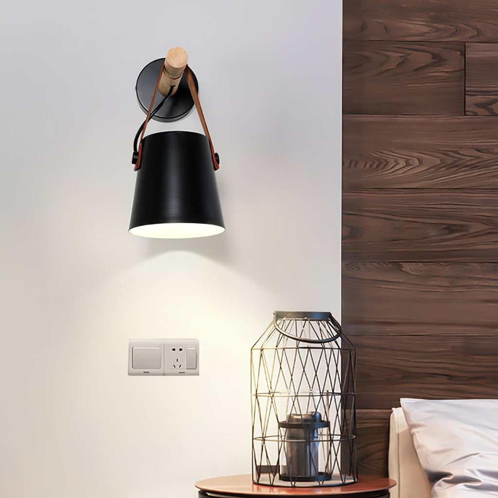 Black Clérachic wall light beside a dark wood-panelled wall, above a wire lantern and a wall socket.