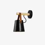 Black Clérachic wall light shown on a plain light backdrop, its shade hanging from the wooden bar on a leather strap.