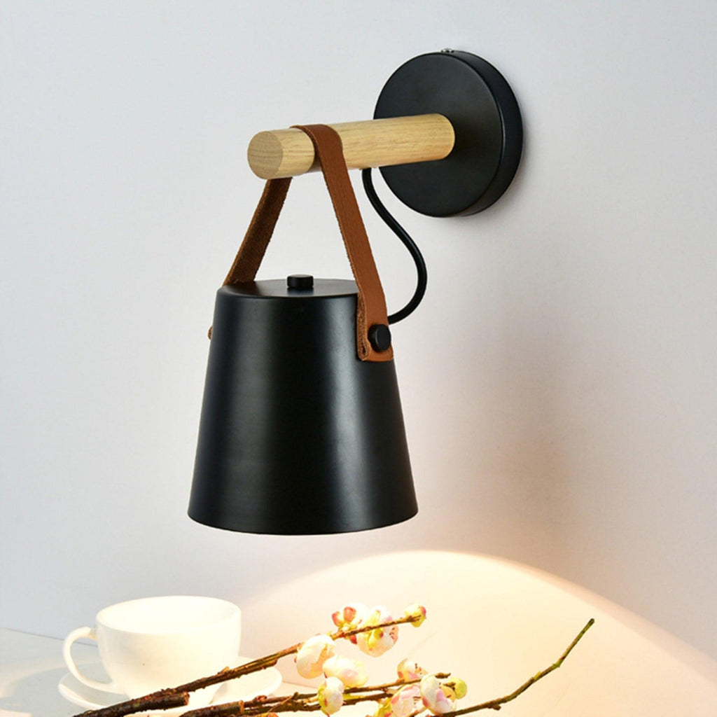 Black Clérachic wall light seen from slightly above, with a teacup and a spray of blossom lit by its glow below.