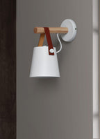 White Clérachic wall light on a grey wall, its wooden bar and leather strap standing out against the shade.