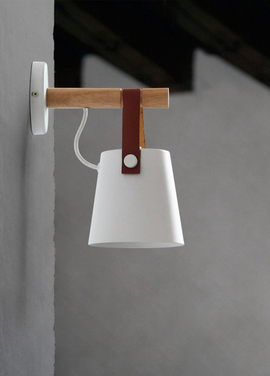White Clérachic wall light on a grey wall with a dark ceiling beam, seen from the side with its white cord.