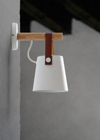 White Clérachic wall light on a grey wall with a dark ceiling beam, seen from the side with its white cord.