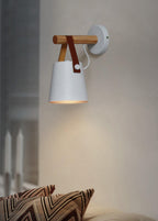 White Clérachic wall light on a warm grey wall above a sofa with zigzag-patterned cushions.