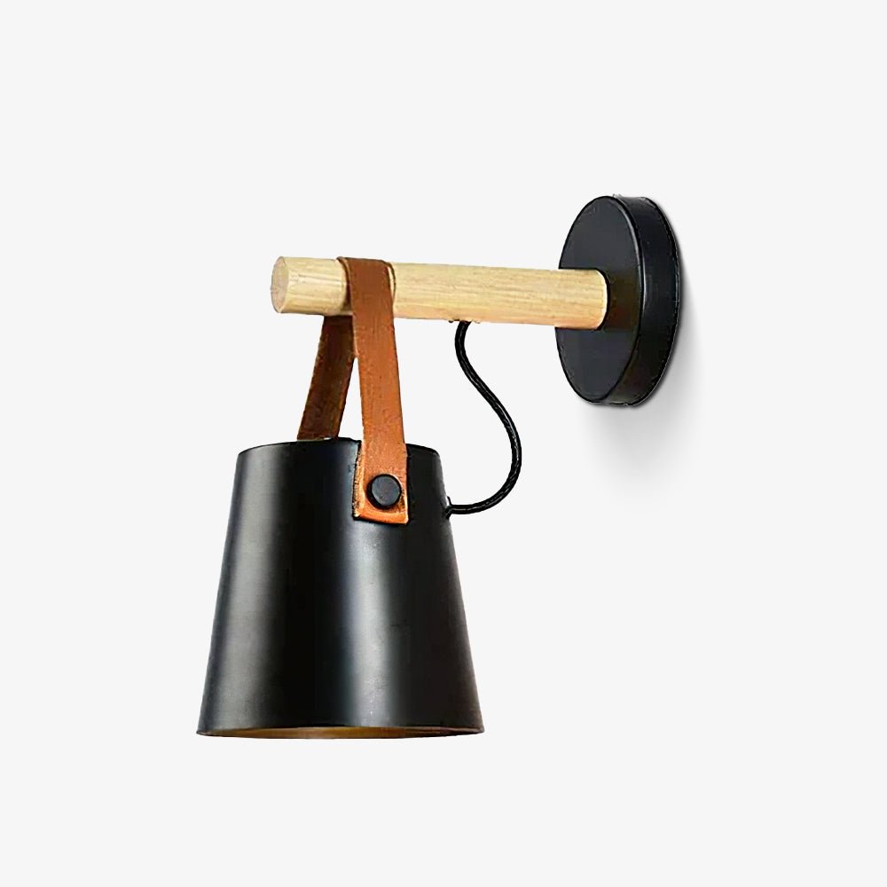 Black Clérachic wall light on a plain light backdrop, with a tan leather strap fastened by a black button.