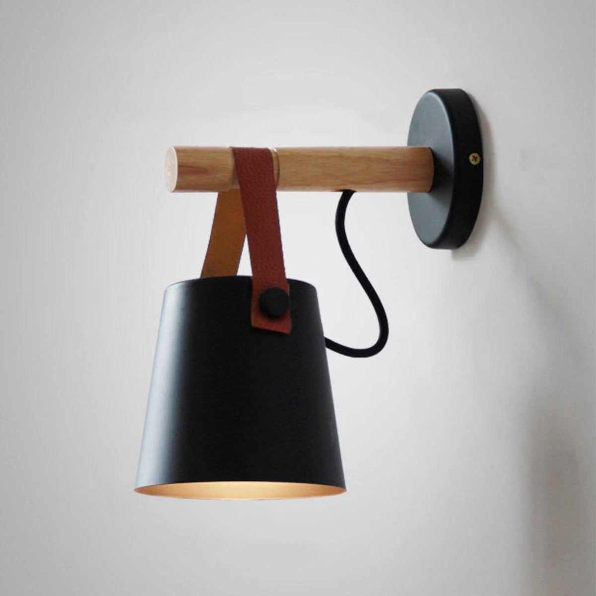 Large close view of a black Clérachic wall light on a pale wall, its inner shade glowing warm beneath the wooden bar.